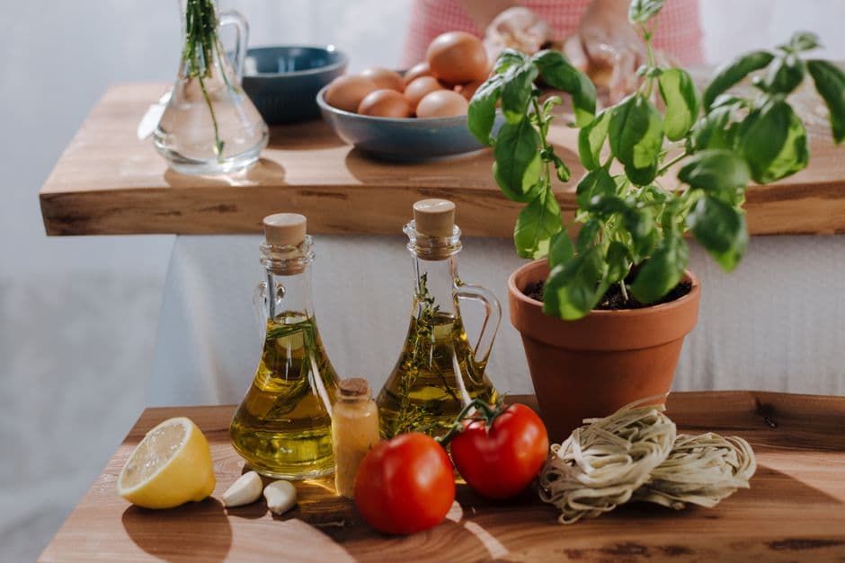 Fresh cooking ingredients — tomatoes, olive oil and basil — laid out on a wooden table, ready to find a recipe using what you have at home