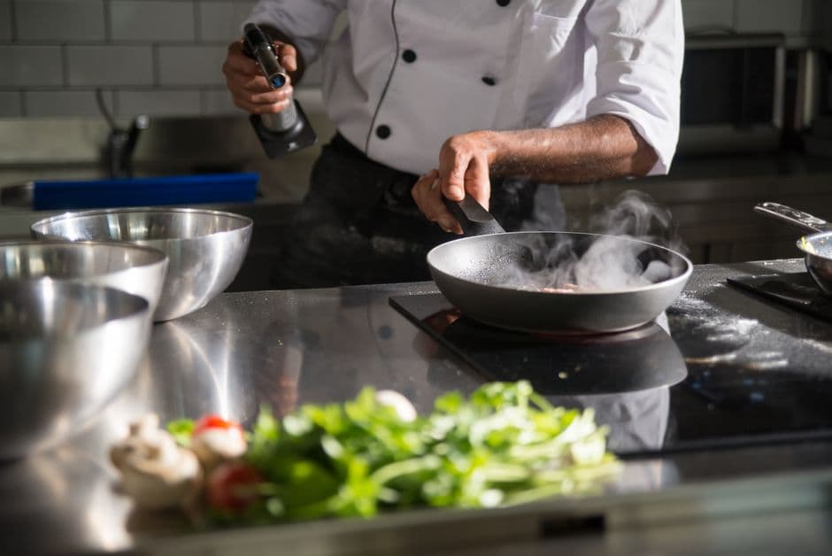 Home cook preparing a recipe on an induction cooktop, using fresh ingredients already in the kitchen with no shopping trip needed