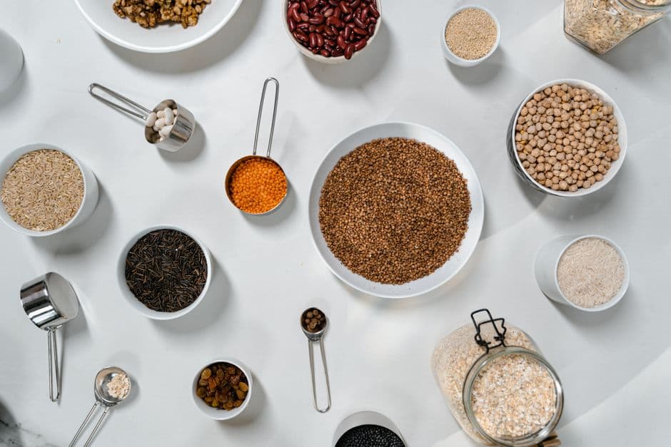 Top view of assorted pantry ingredients — grains, legumes and spices arranged in bowls and jars — for cooking recipes using ingredients already at home